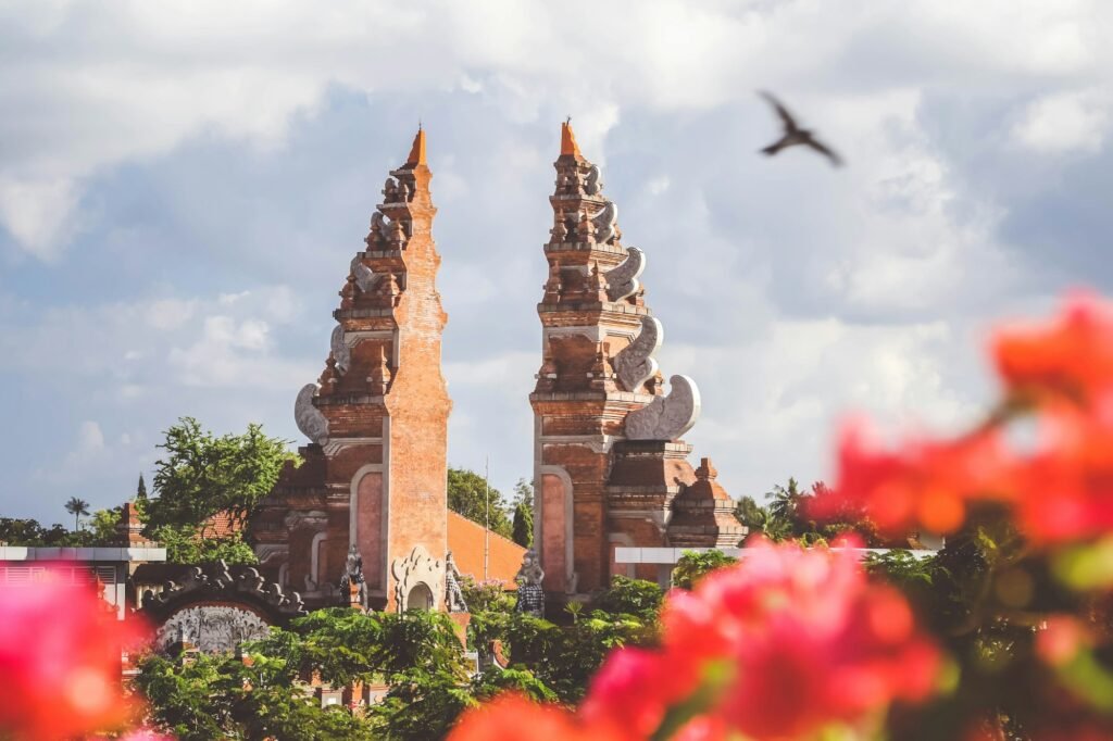 Split gate of a Balinese temple framed by tropical flowers